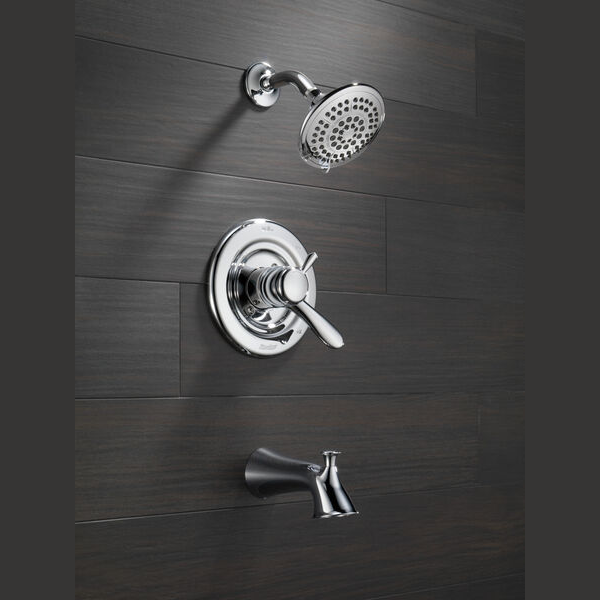 Chrome tub and shower faucet trim set with adjustable showerhead and single lever control on dark wall paneling