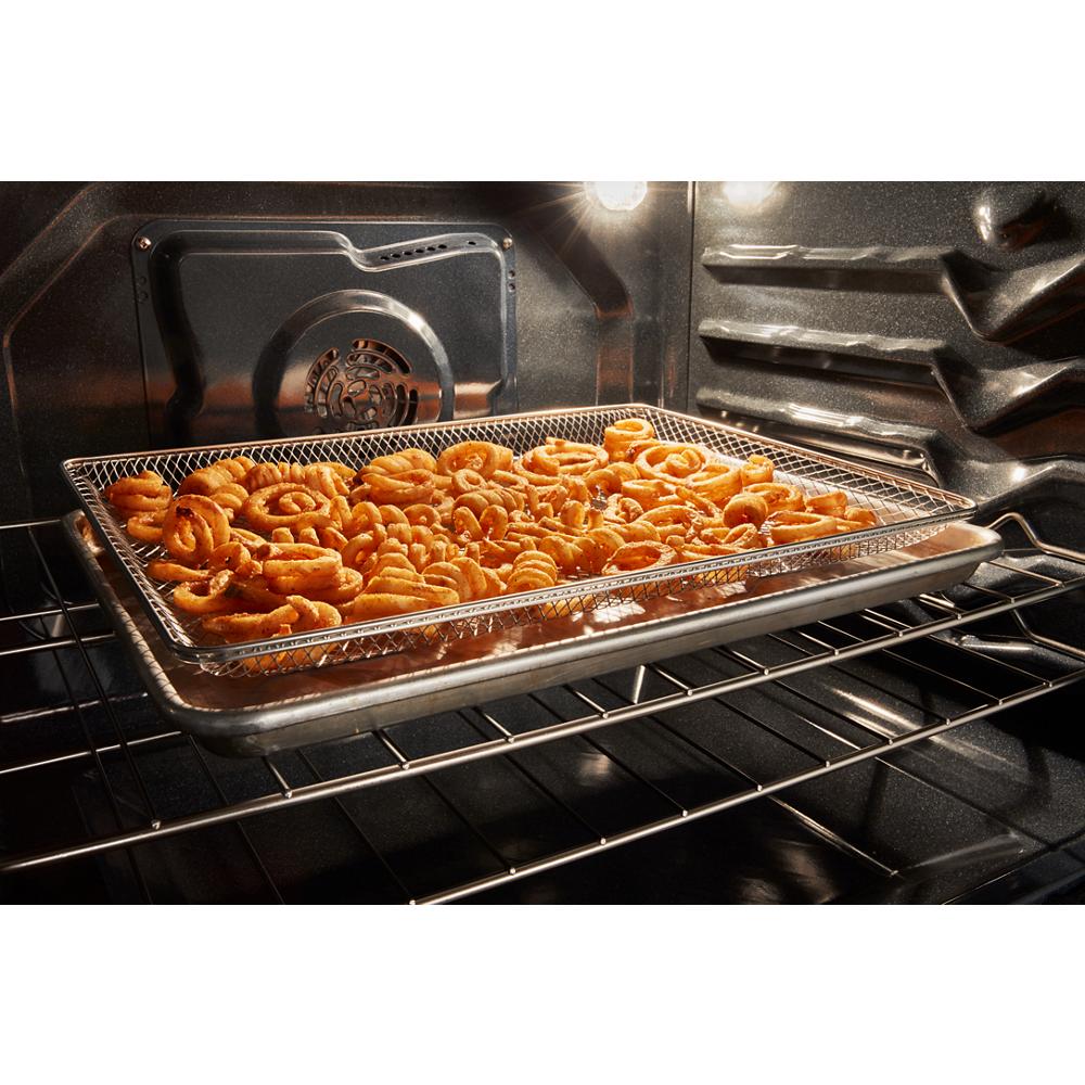 Curly fries air frying on a wire rack inside a modern electric range oven from the Ranges collection.
