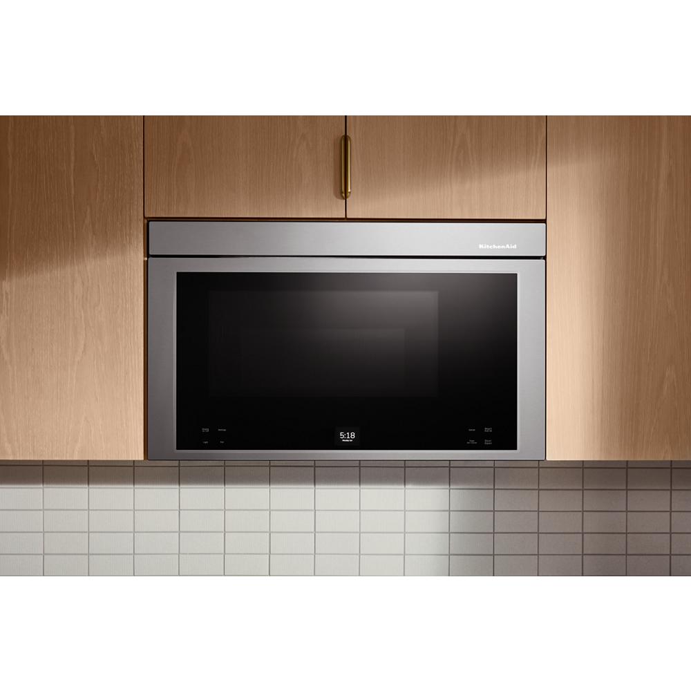Stainless steel multifunction over-the-range oven installed flush within wood cabinetry above white tiled backsplash
