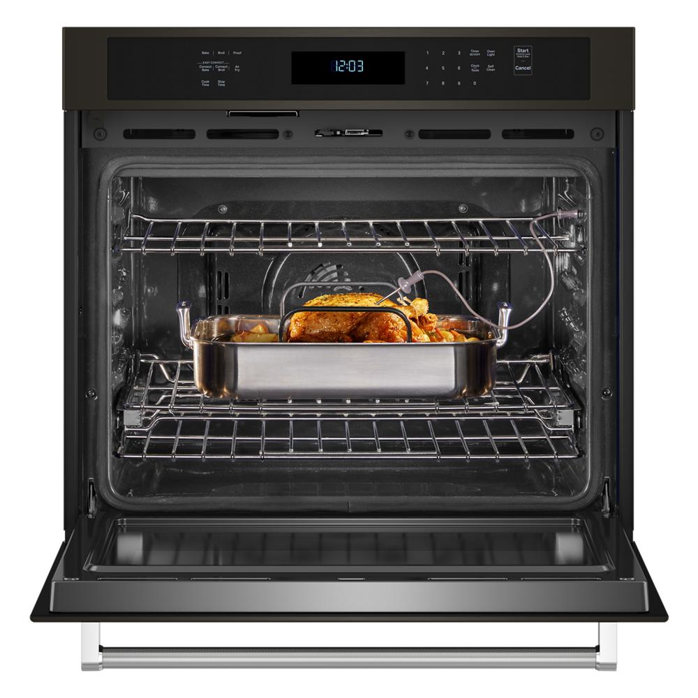 Open KitchenAid black stainless steel wall oven roasting whole chicken with thermometer probe inserted inside oven cavity