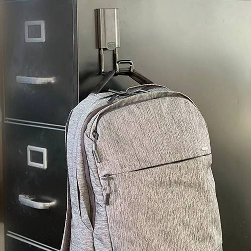 Black closed magnetic hook supporting a grey backpack on a metal filing cabinet for tools and home improvement use