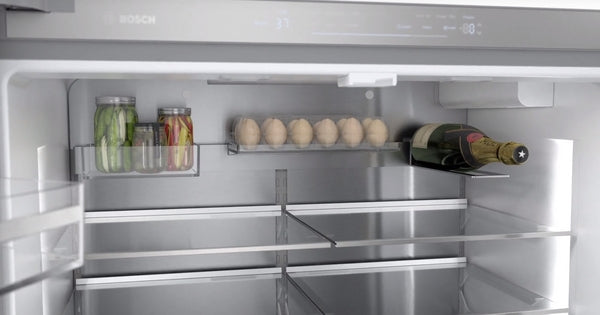 Interior view of a stainless steel French door refrigerator with glass shelves and organized storage compartments