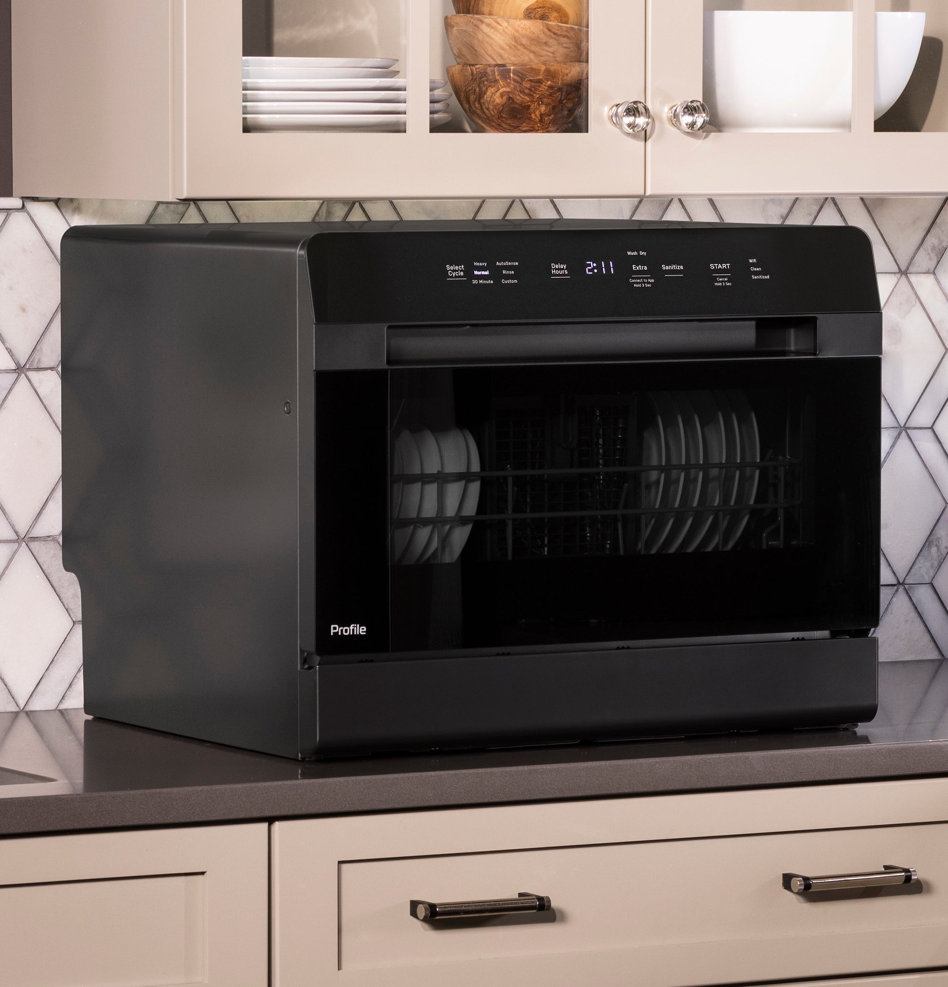 Black compact countertop dishwasher with digital control panel and dishes inside on kitchen countertop surface