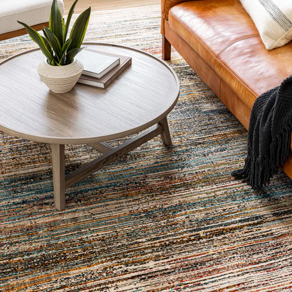 Textured area rug with abstract oyster and neutral tones beneath round coffee table and leather sofa in home decor setting