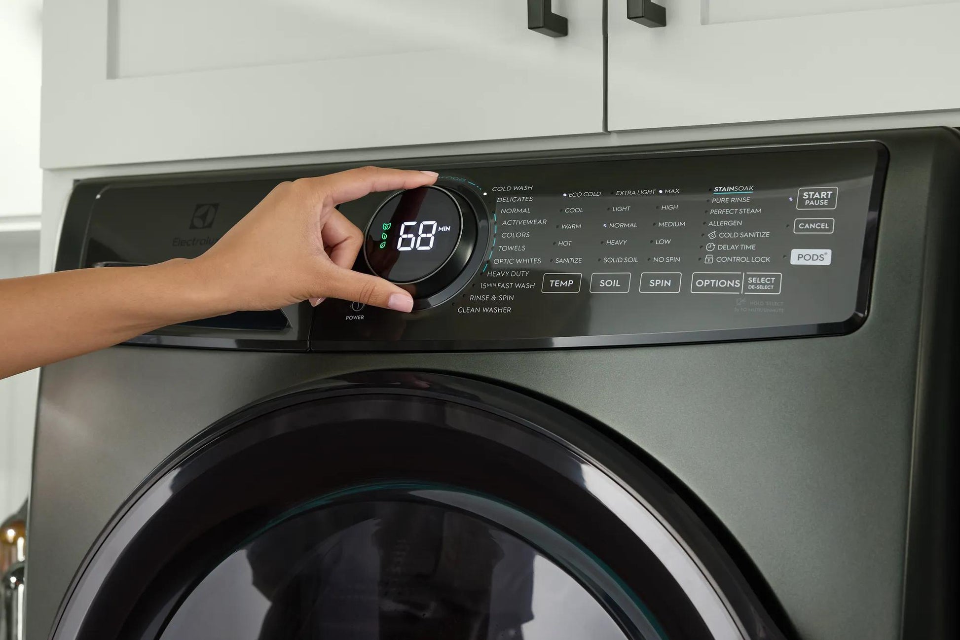Hand adjusting dial on dark gray front load washer digital control panel from washers and appliances collection