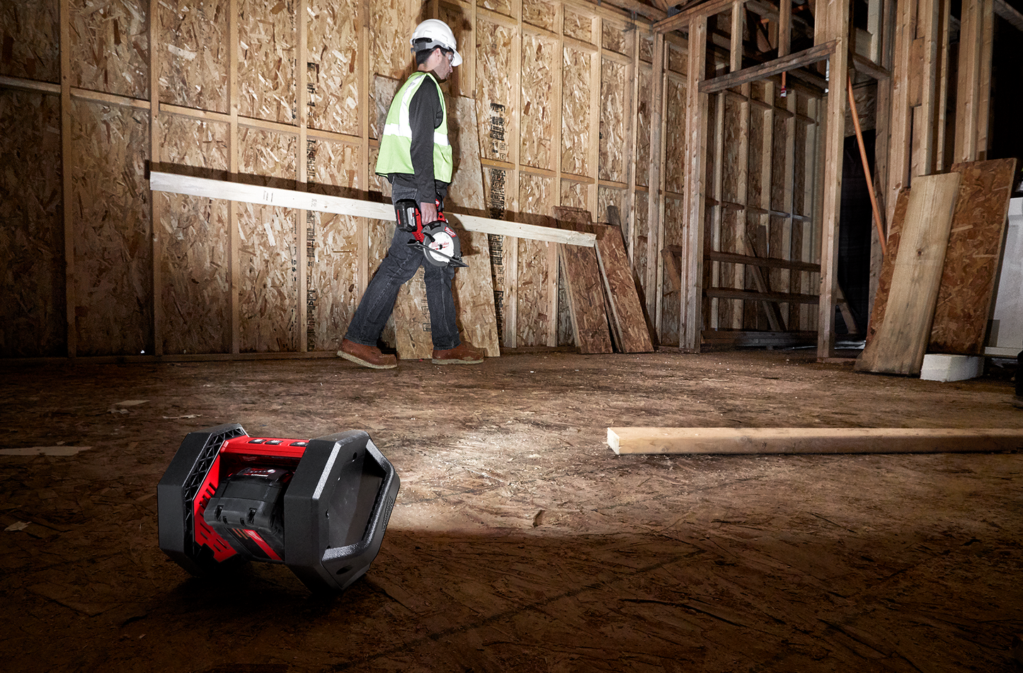 Compact Milwaukee portable flood light casting bright illumination in wood-framed construction site from Work Lights collection