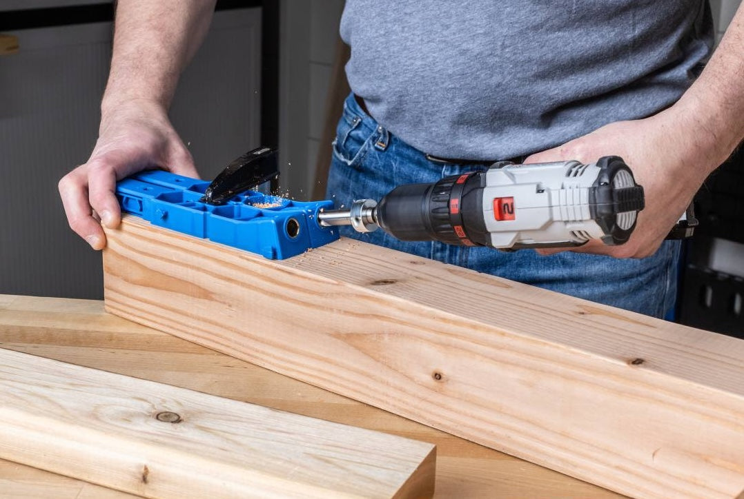 Blue pocket-hole jig with hardened steel guides used for drilling precise joints in large wood boards for woodworking projects