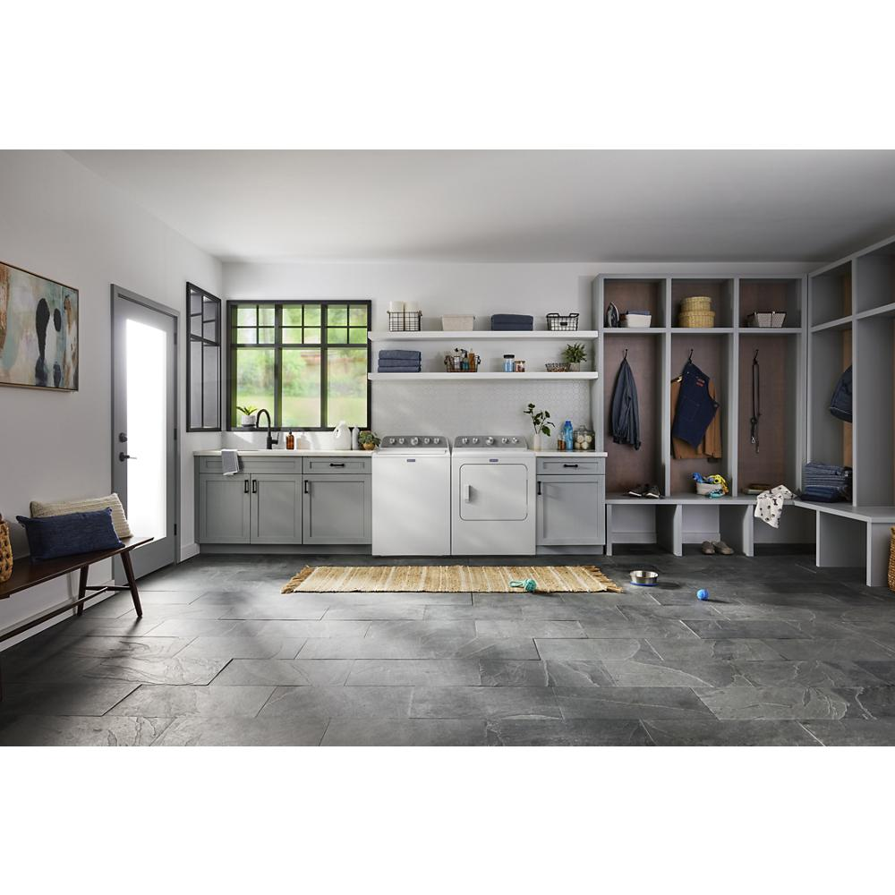 Laundry room with white top load washer and dryer set, gray cabinets, bench, and organized storage for a home appliances setting.