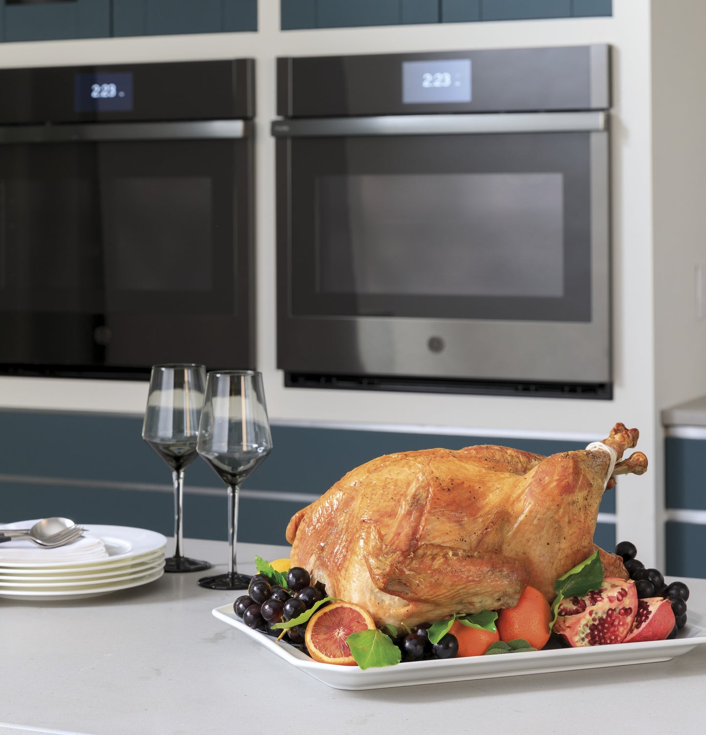 Roast turkey with fruit garnish on counter in front of stainless steel smart convection double wall ovens in modern kitchen