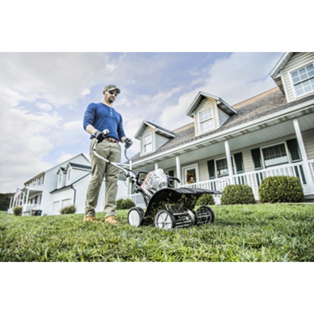Man using a gas-powered tiller with wheel kit to cultivate soil on a residential lawn for home improvement tasks