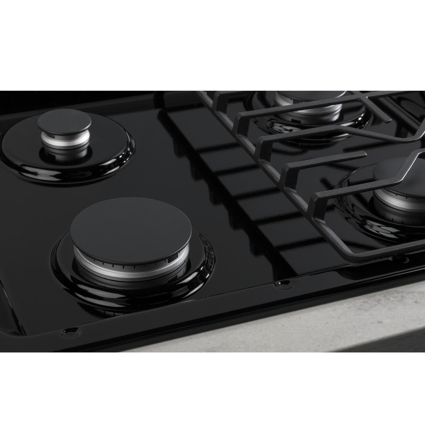 Close-up view of black built-in gas cooktop burners with dishwasher-safe grates in modern kitchen setting