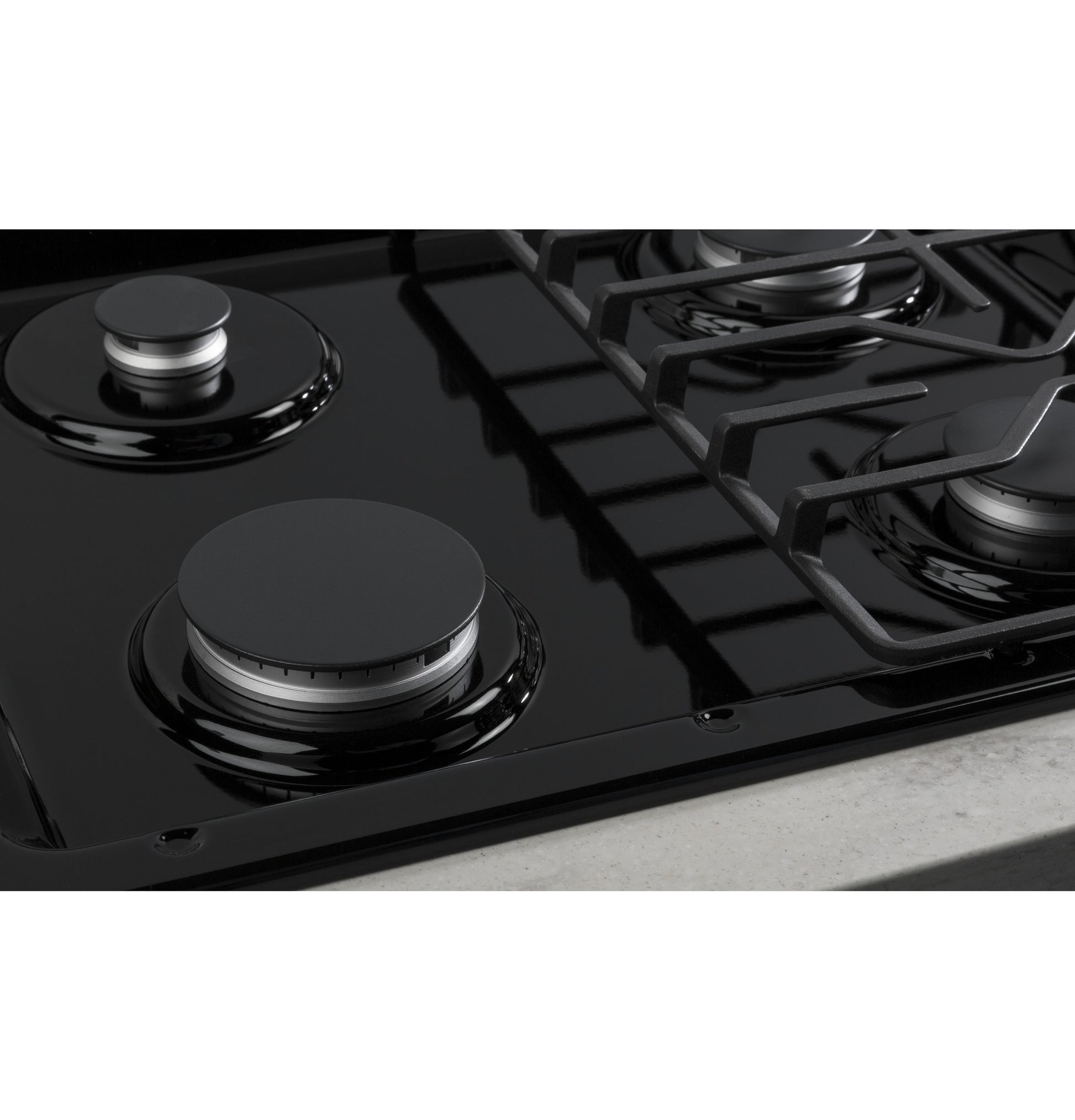 Close-up view of black built-in gas cooktop burners with dishwasher-safe grates in modern kitchen setting