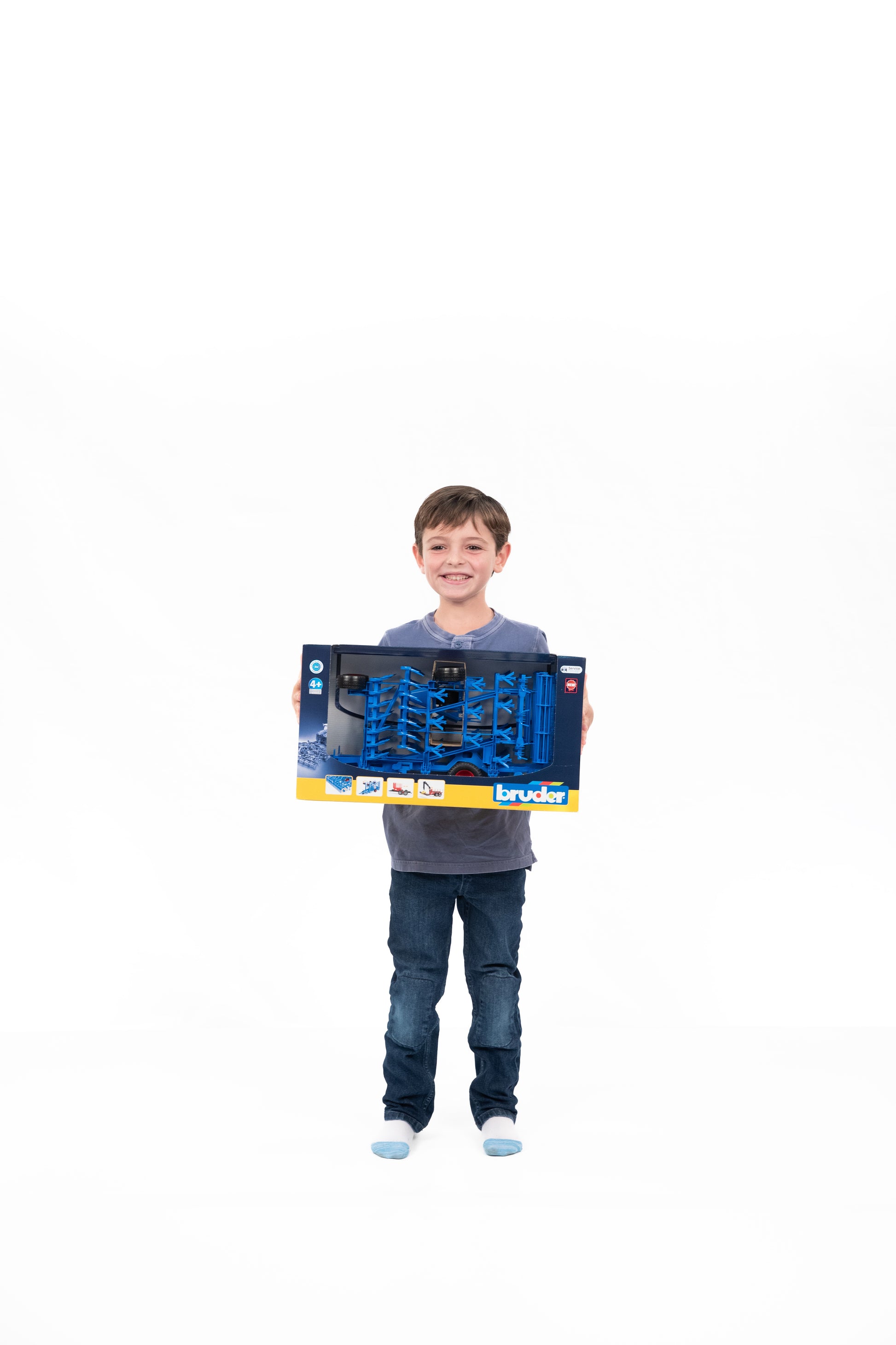 Child holding boxed blue model cultivator toy from Bruder for tools and home improvement play