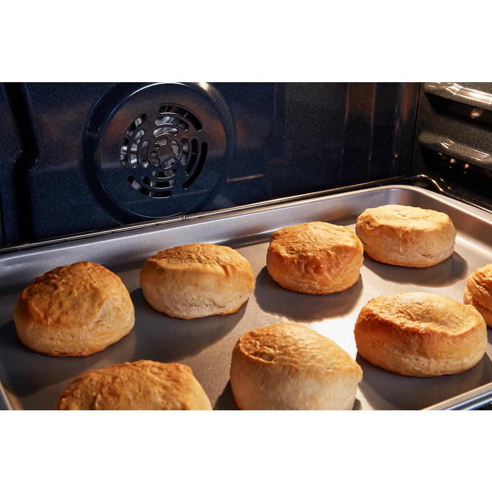 Golden biscuits baking on a metal tray inside an electric oven with visible interior fan for even cooking.