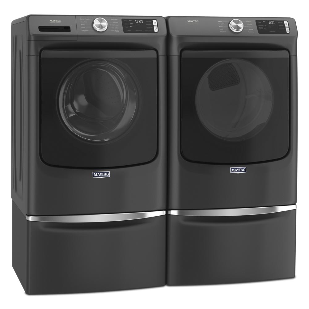 Matte black front load washer and gas dryer pair with digital displays and pedestal drawers in modern laundry setting