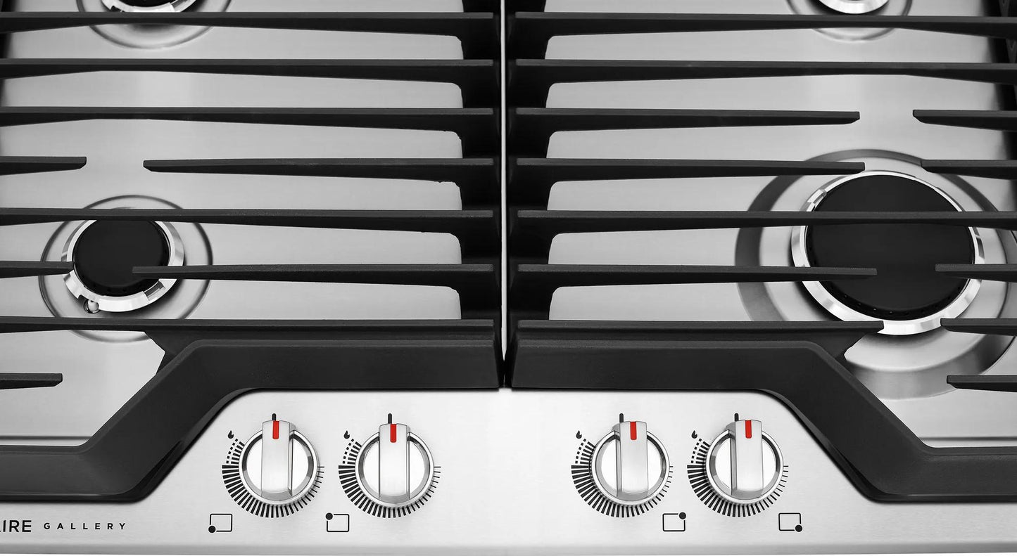 Close-up of stainless steel cooktop burners with black cast iron grates and silver control knobs from Cooktops collection