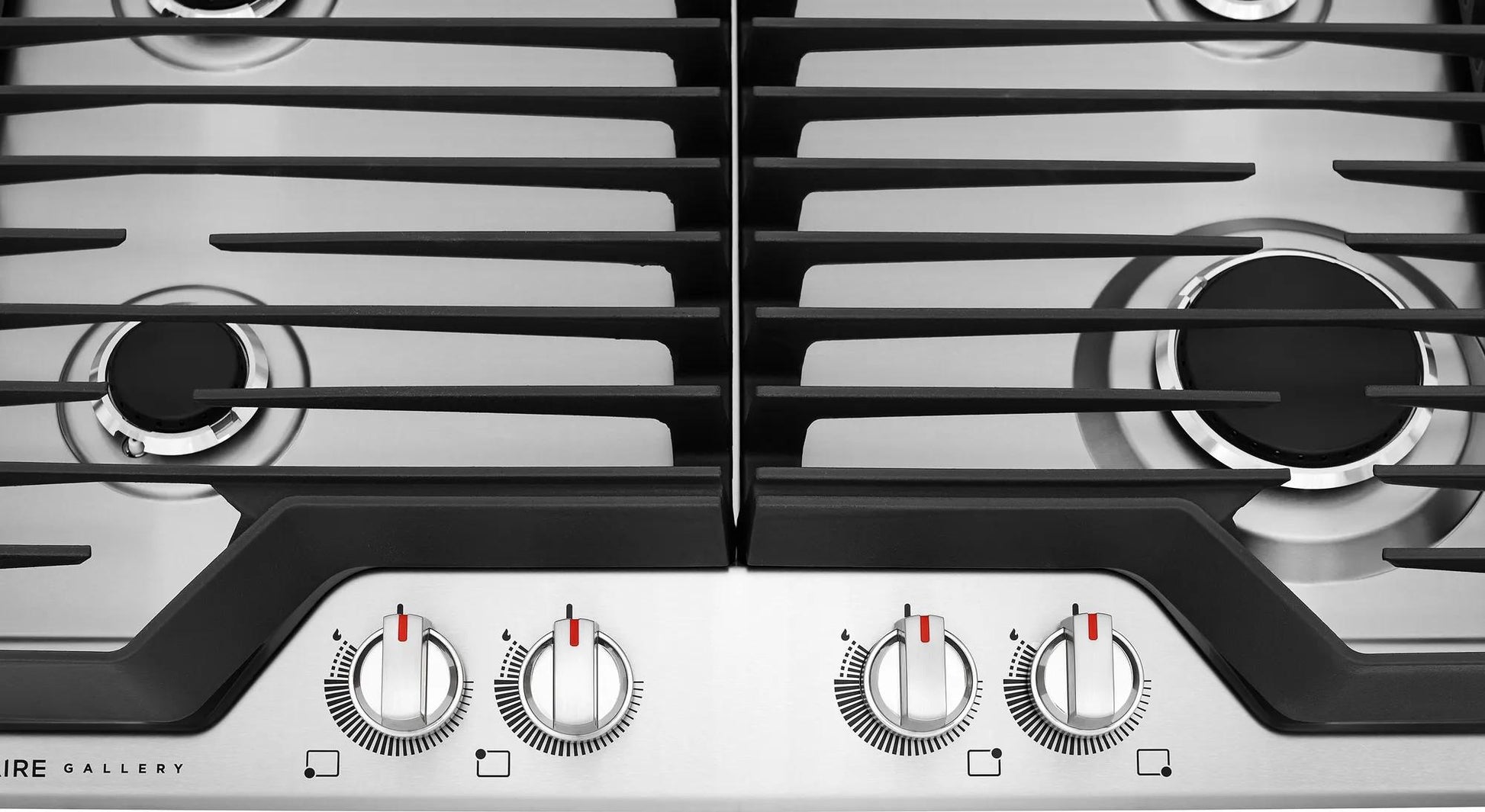 Close-up of stainless steel cooktop burners with black cast iron grates and silver control knobs from Cooktops collection