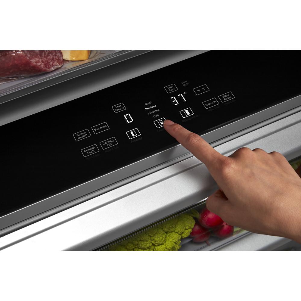 Close-up of a hand adjusting the digital temperature control panel on a built-in side-by-side refrigerator from KitchenAid collection