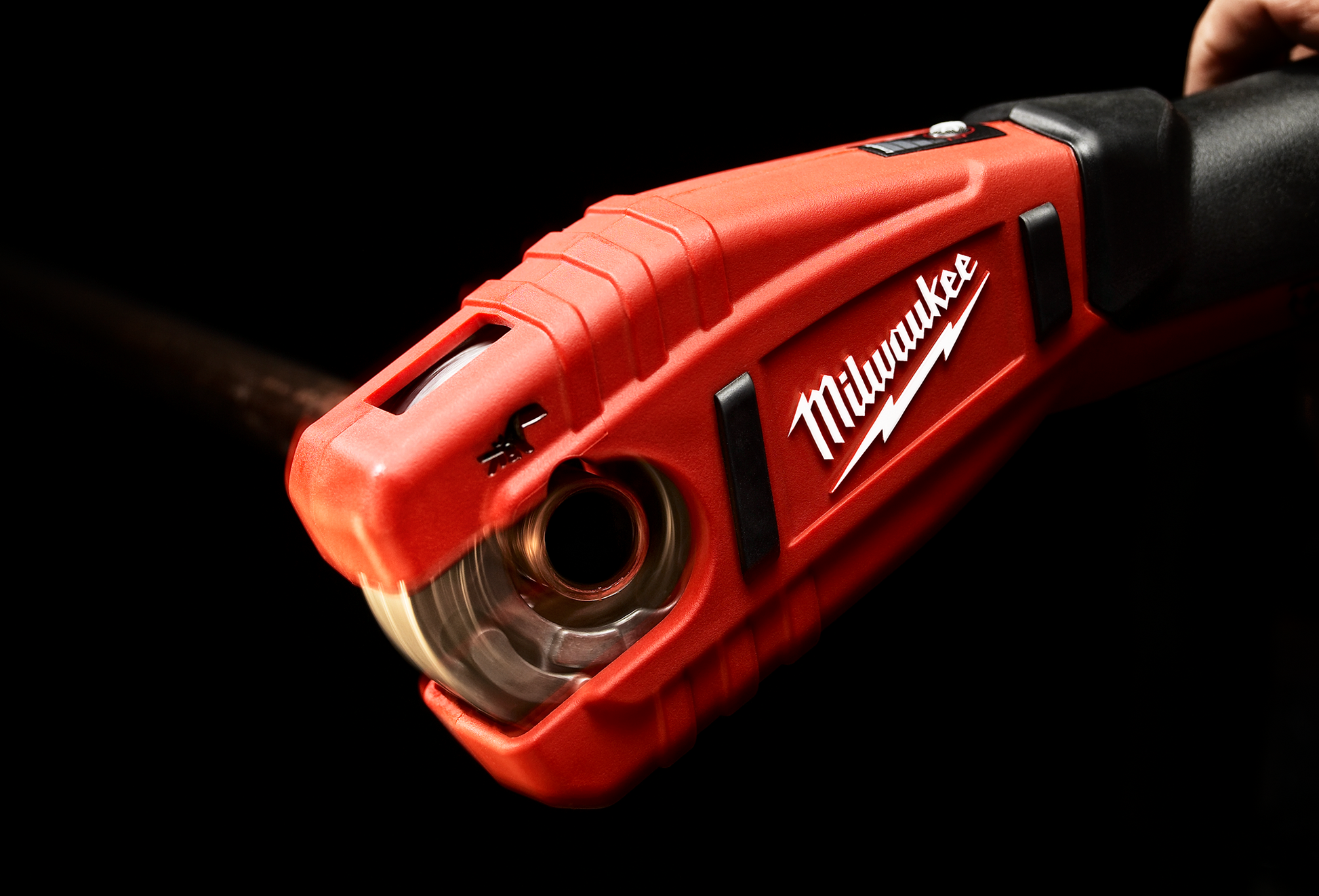 Red Milwaukee cordless copper tubing cutter tool cutting pipe in plumbing and home improvement context