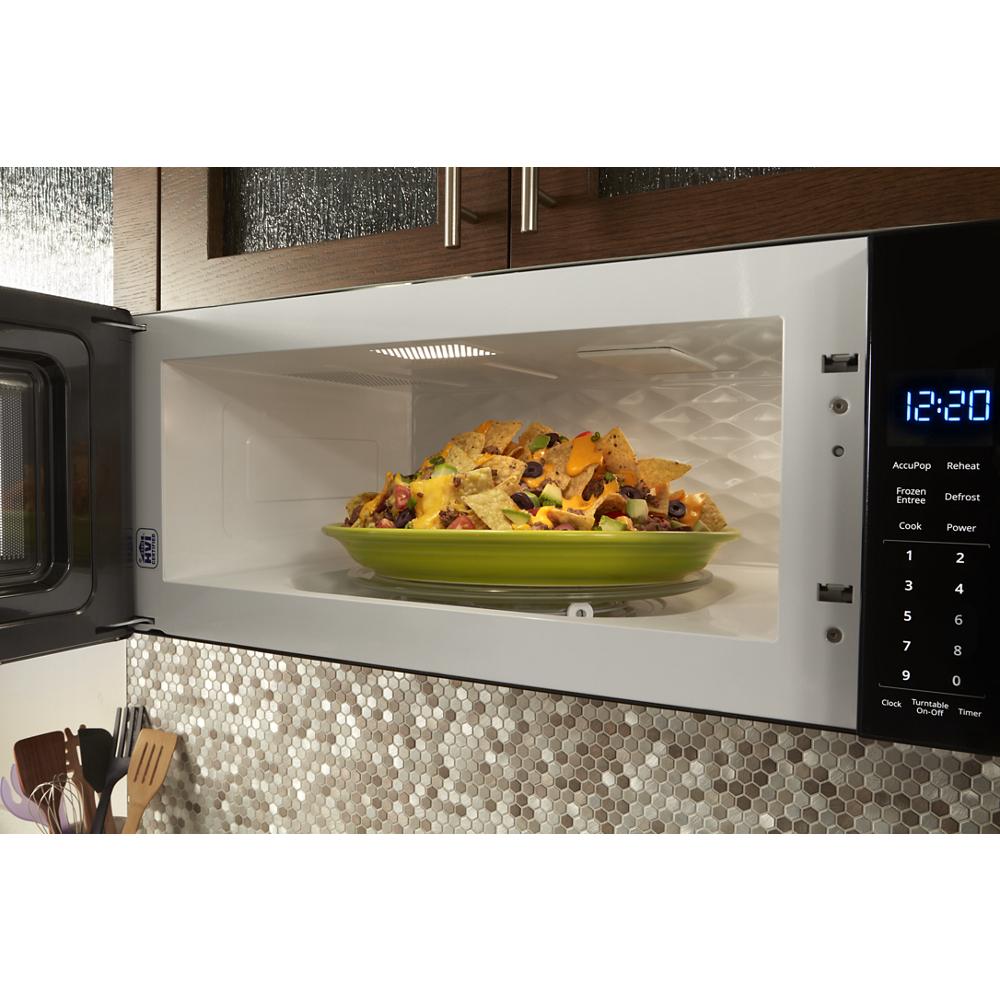 Open low profile microwave hood combination interior showing plate of nachos on turntable and digital control panel lit at 12:20