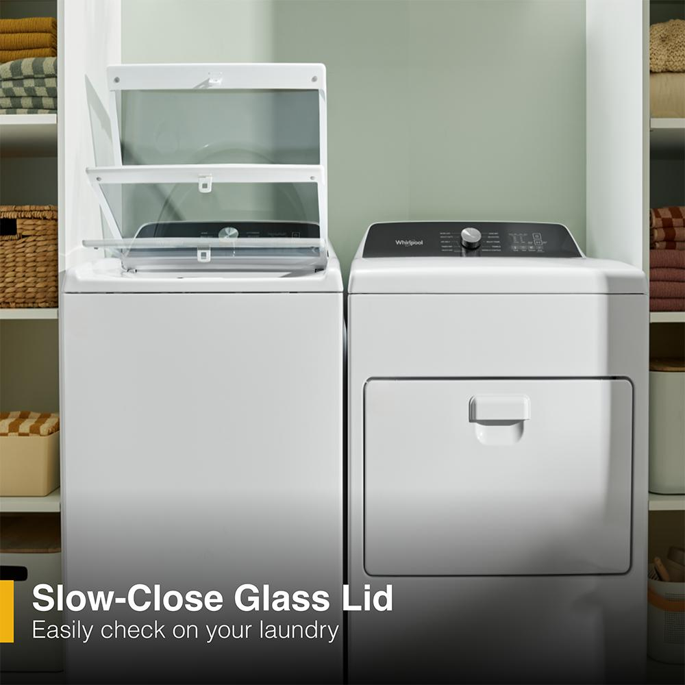 White top load washer with open glass lid and matching front load dryer in organized laundry space with shelves