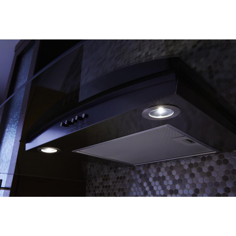 Black concave glass wall mount range hood with LED task lighting and control buttons in modern kitchen setting
