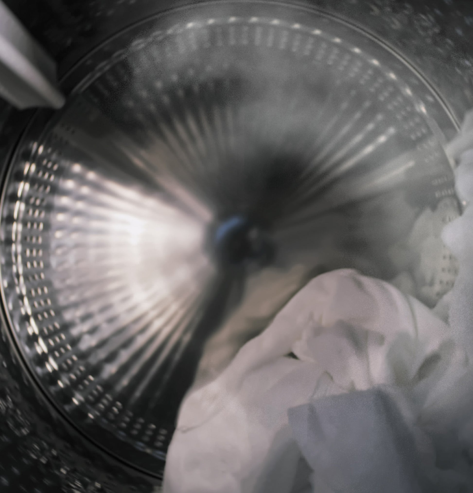 Interior view of a front load washer drum in motion with white clothes inside in the Washers & Dryers collection