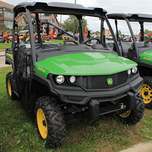 Green full-size crossover utility vehicle with protective cab and durable tires for outdoor work and home improvement tasks
