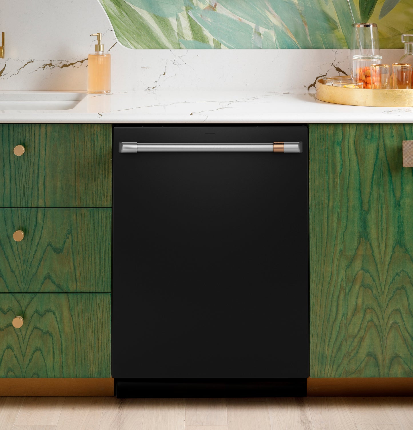 Black dishwasher with stainless steel handle integrated into green wood cabinetry under white marble countertop in modern kitchen.