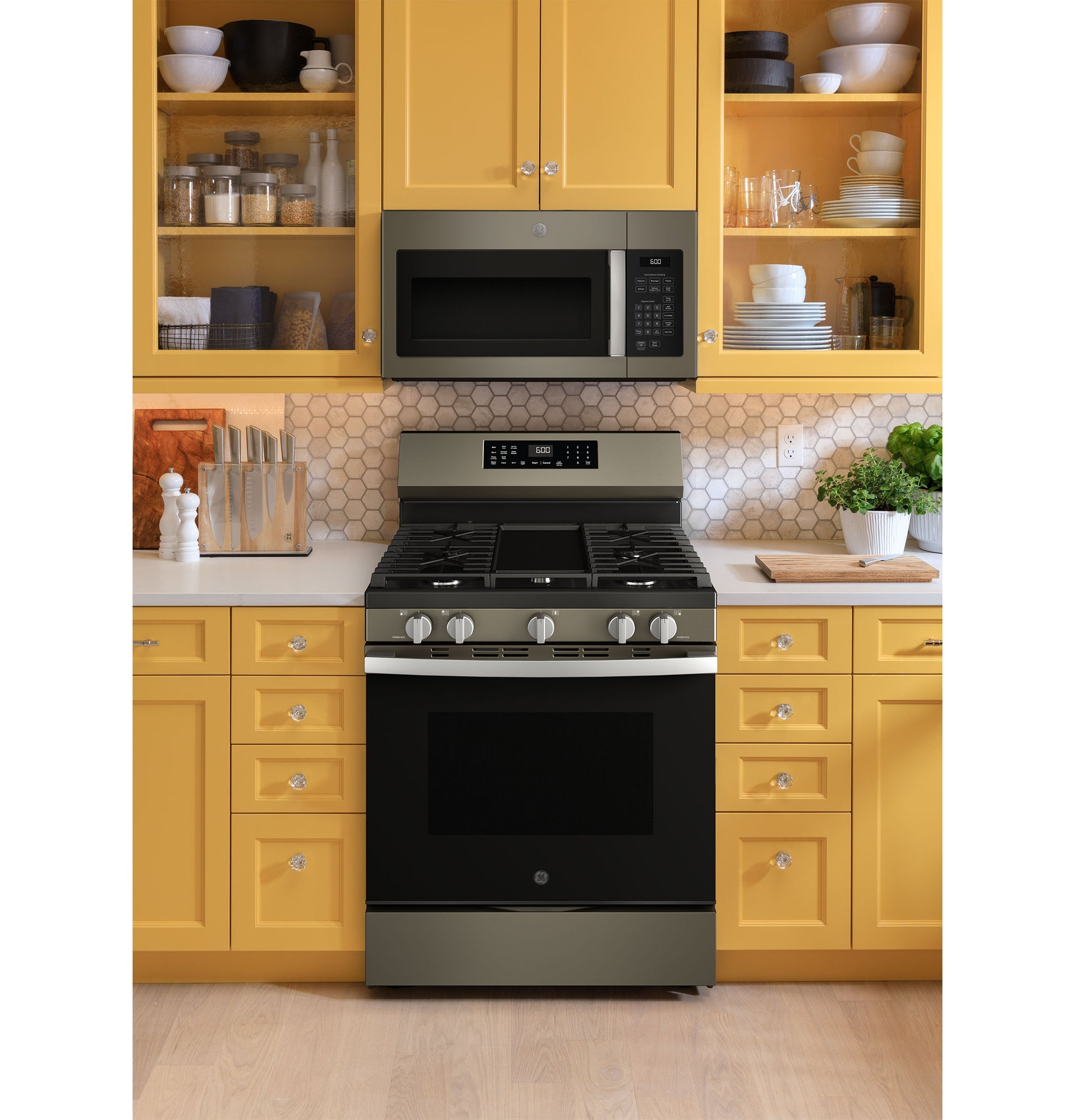 GE free-standing gas convection range installed in yellow cabinetry kitchen with white countertop and hex tile backsplash