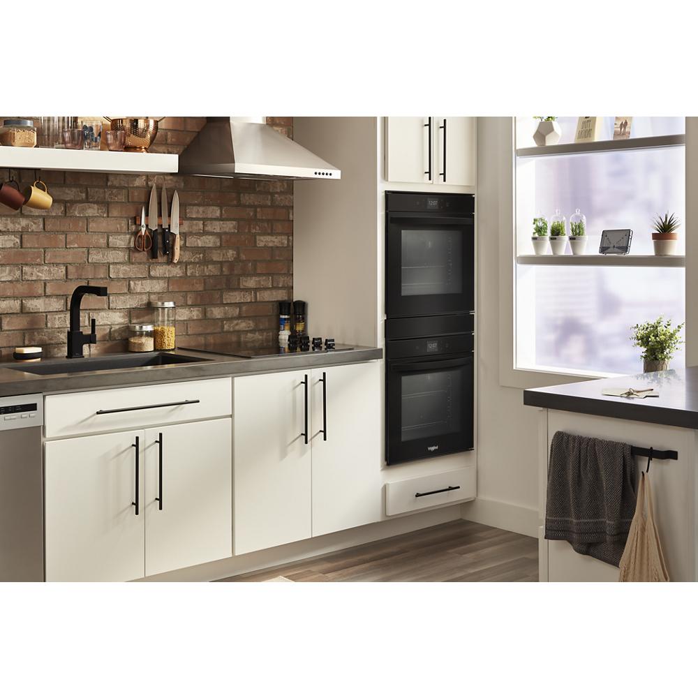 Built-in black double wall oven with convection in white kitchen featuring brick backsplash and modern cabinet hardware