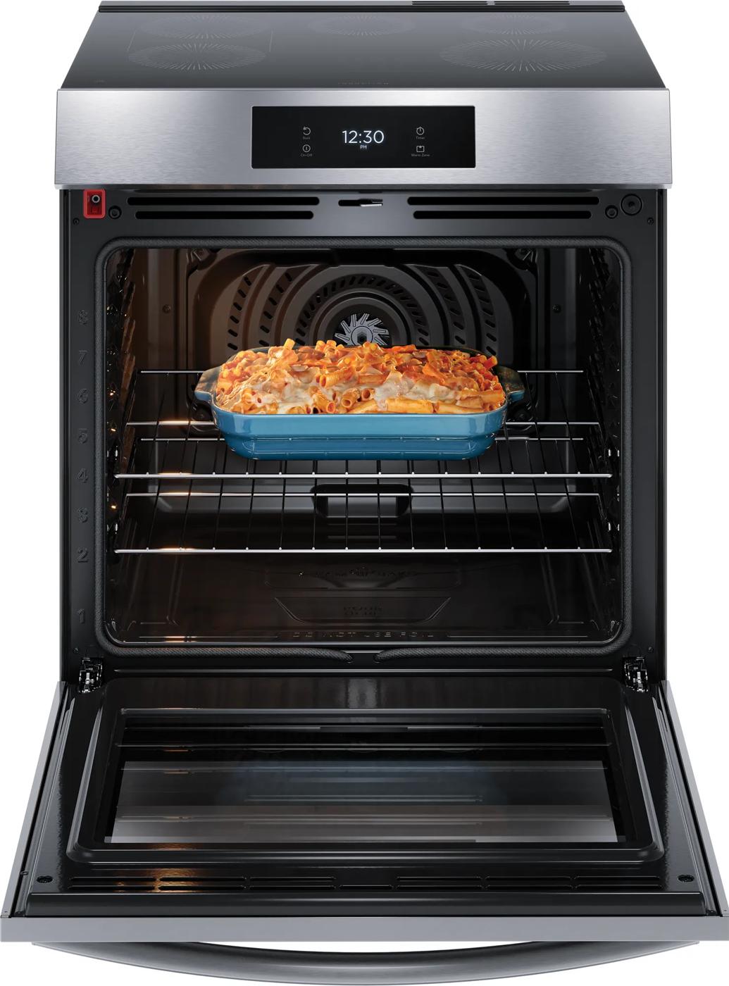 Open stainless steel front control induction range oven with blue casserole dish of baked pasta inside for kitchen appliances and ranges collection