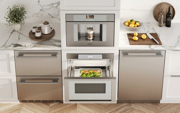 Built-in stainless steel microwave drawer open with meal inside in modern kitchen with marble countertop and wood flooring