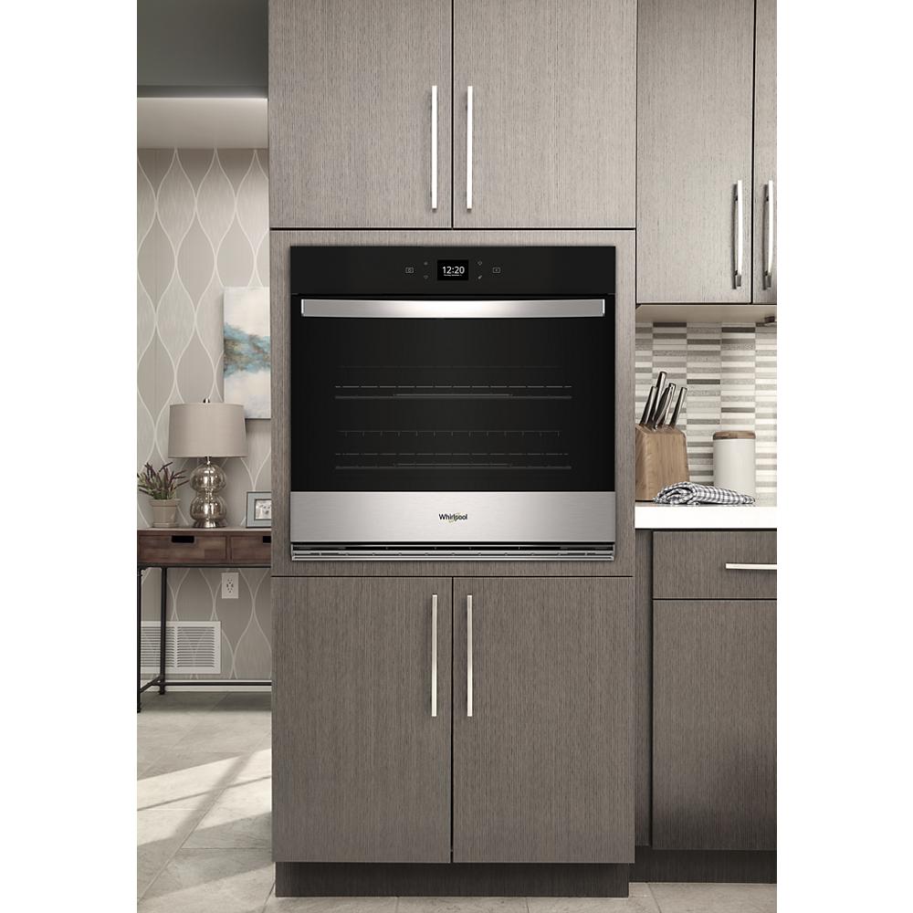 Built-in stainless steel wall oven with digital clock and modern handle in kitchen appliances collection