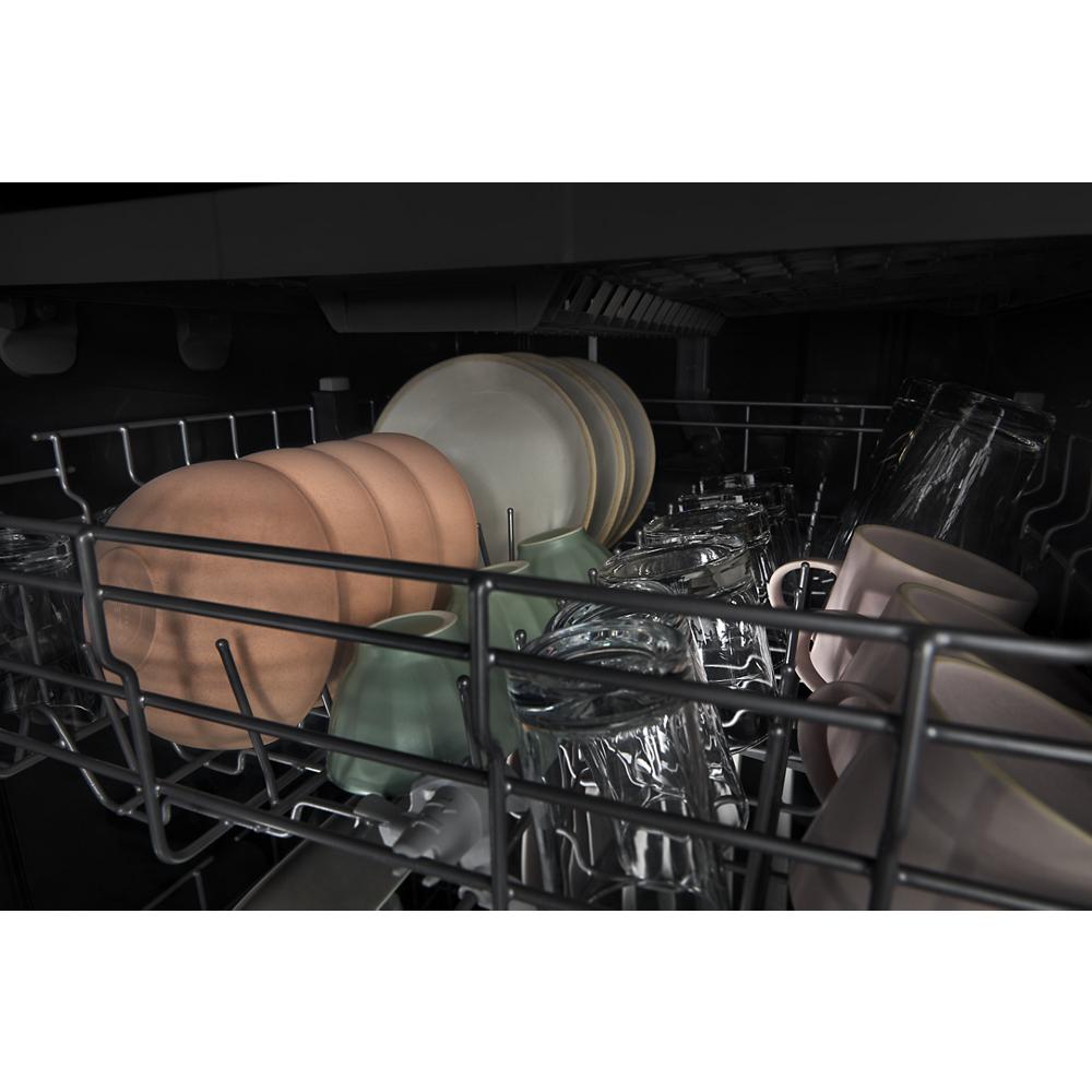 Bottom rack of dishwasher loaded with dishes, glassware, and mugs inside appliance in kitchenware collection