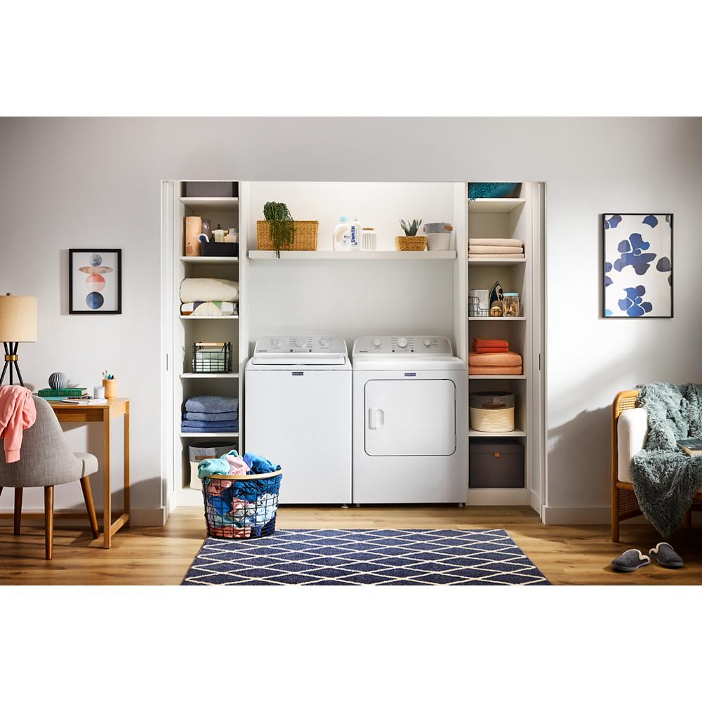 Laundry room setup with white top load washer and dryer surrounded by organized shelves and home decor accents