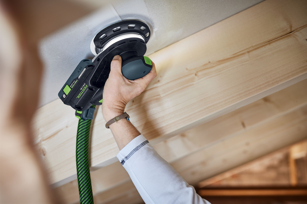Person using cordless orbital sander on wooden surface in woodworking tools and power tools collections