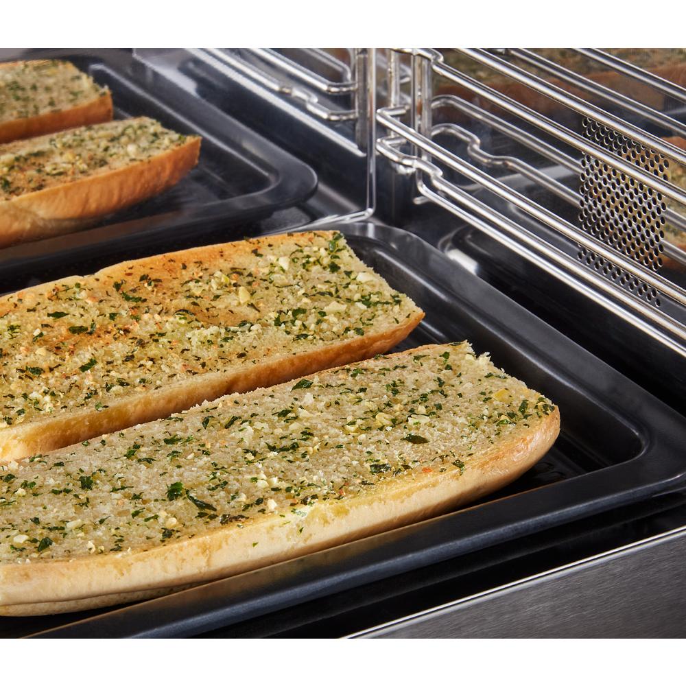 Garlic bread toasting on black tray inside stainless steel multifunction over-the-range oven with built-in design