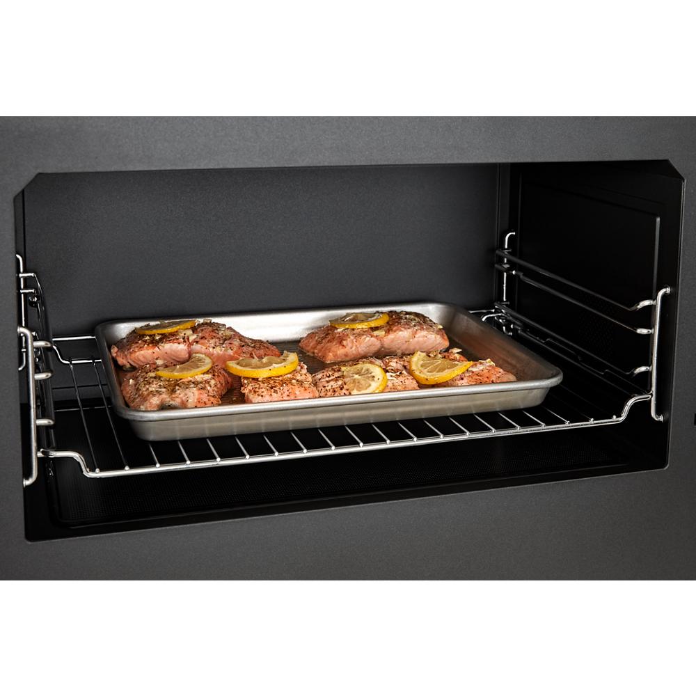 Raw salmon fillets topped with lemon slices cooking on a rack inside an over-the-range microwave oven