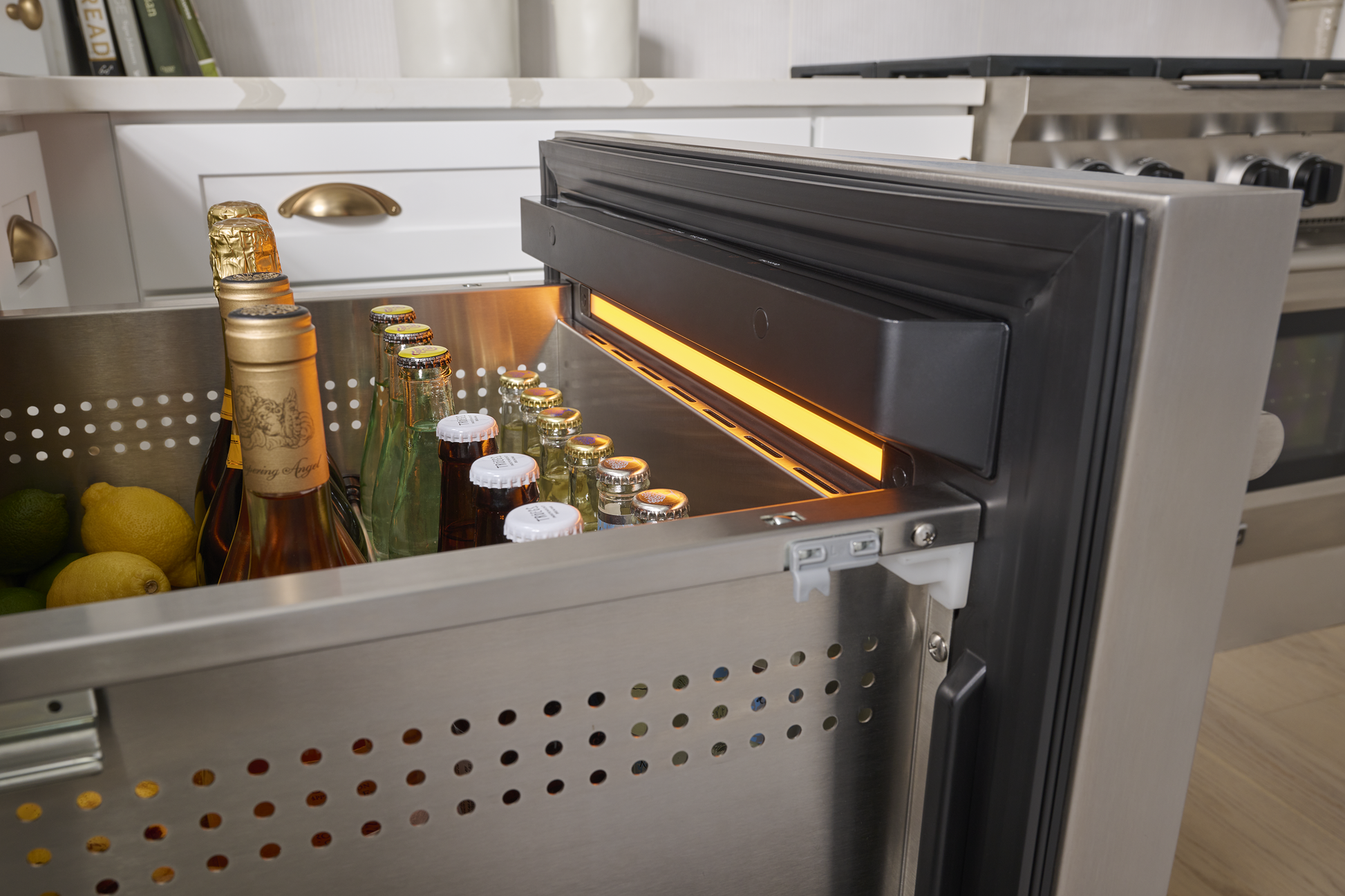 Under-counter stainless steel refrigerator drawer open with chilled beverages in modern kitchen appliances collection