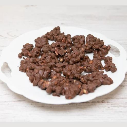 Milk chocolate peanut clusters arranged on a white plate, part of Chocolates & Candies collection under $50