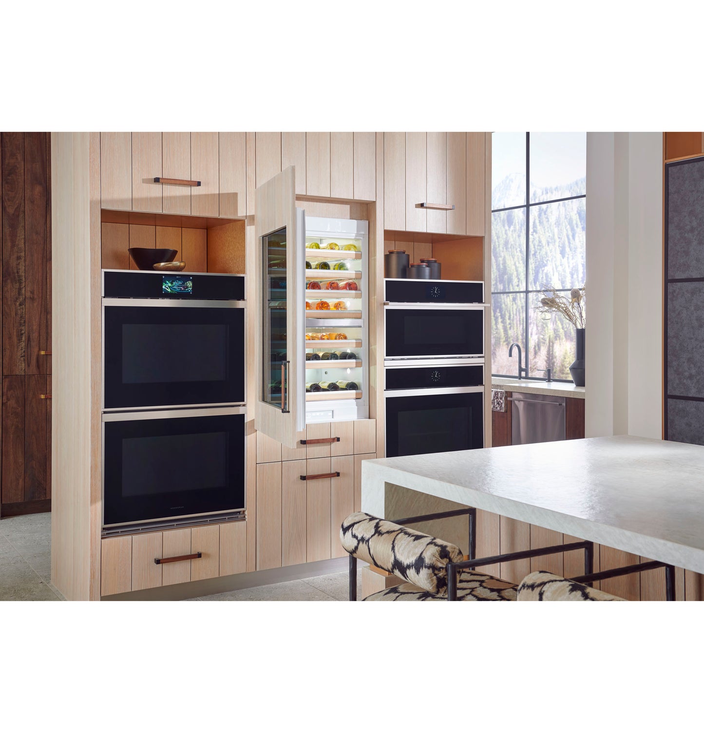 Contemporary kitchen with Monogram minimalist double wall ovens and built-in beverage cooler surrounded by light wood cabinetry