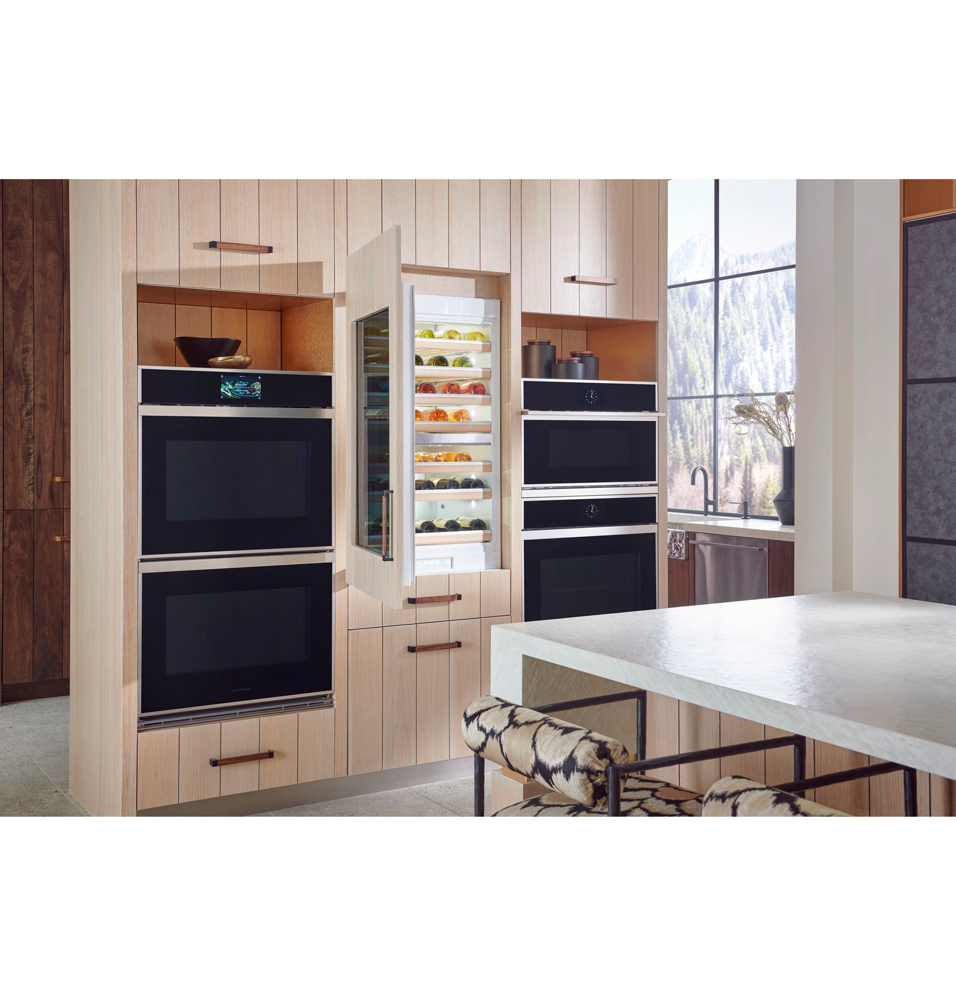Contemporary kitchen with Monogram minimalist double wall ovens and built-in beverage cooler surrounded by light wood cabinetry