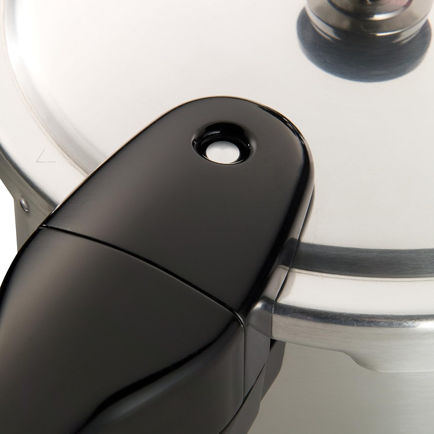 Close-up of black handle with safety valve on polished aluminum pressure cooker in kitchenware and small appliances collections