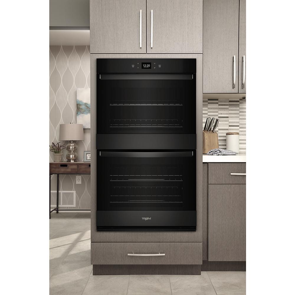 Black Whirlpool double wall oven with digital controls installed in modern kitchen cabinetry for home improvement