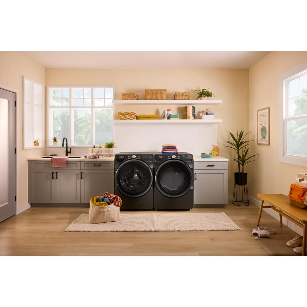 Bright laundry room with dark gray smart front load washer and gas dryer, beige walls, gray cabinetry, and natural light in appliances collection