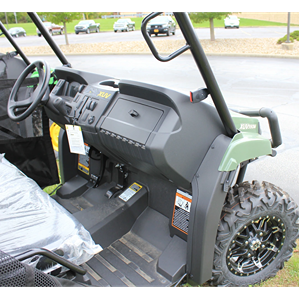 Interior view of green mid-size utility vehicle showing dashboard, steering wheel, and rugged off-road tires
