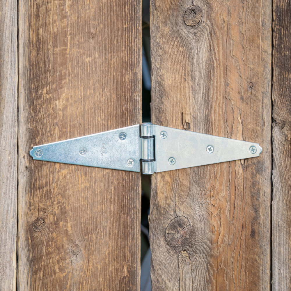 Zinc heavy-duty strap hinge mounted on rustic wooden barn door for home improvement and hardware projects