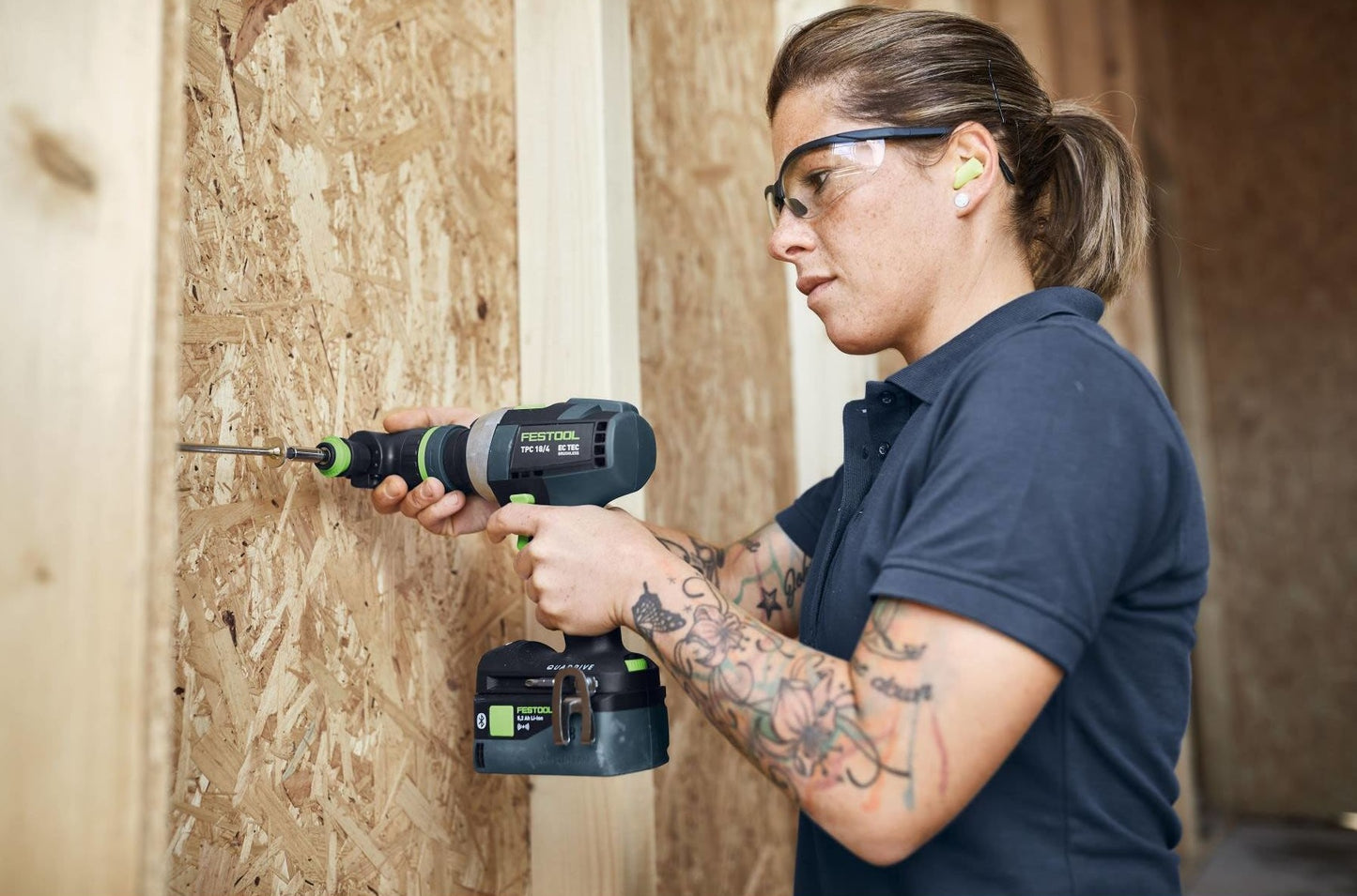 Person wearing safety glasses using a cordless power drill on wood in a woodworking tools setting