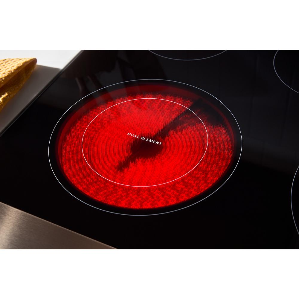 Close-up of glowing red dual element induction cooktop burner on sleek black glass surface from kitchen appliances collection